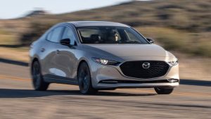 Silver Mazda driving down a road 